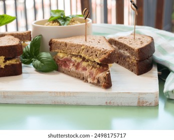 Toasted rye bread sandwich with sliced Italian ham and creamy homemade avocado cashew spread on white wooden board. Light summer easy recipe lunch - Powered by Shutterstock