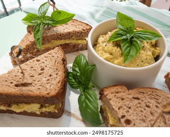 Toasted rye bread sandwich with sliced Italian ham and creamy homemade avocado cashew spread on white wooden board. Light summer easy recipe lunch - Powered by Shutterstock