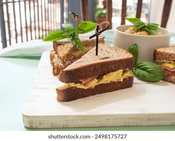 Toasted rye bread sandwich with sliced Italian ham and creamy homemade avocado cashew spread on white wooden board. Light summer easy recipe lunch - Powered by Shutterstock