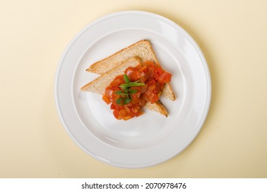 Toasted Sandwich Bread With Tomato Salsa Topped With Sliced Scallions Or Spring Onions Or Green Onions. On White Plate On A Light Yellow Or Beige Or Cream Background. Flat Lay. 