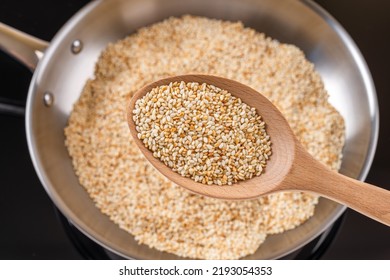 Toasted Sesame Seeds In A Wooden Spoon Over Stainless Steel Skillet. Roasting Organic Benne Grains In A Frying Pan. Sesamum Indicum As Calcium Source For Healthy Eating. Asian Cuisine. Top View.