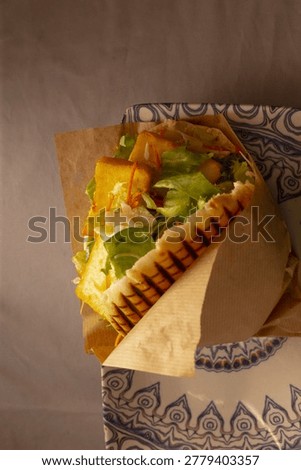 Toasted shawarma with greens on patterned plate, charred marks on wrap revealing fresh lettuce and sauce, vertical framing highlights artisan presentation and latenight