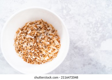 Toasted Shredded Coconut Flakes In A White Ceramic Bowl.