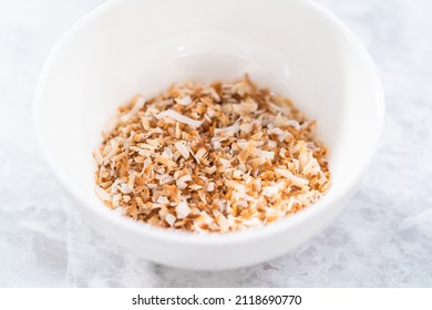 Toasted Shredded Coconut Flakes In A White Ceramic Bowl.