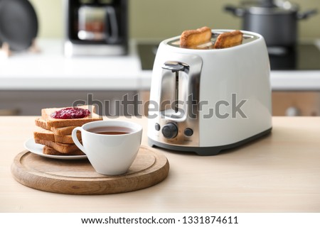 Toaster with bread slices and cup of coffee on table