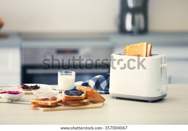 Toaster with dishes and sandwiches on a light\
kitchen table