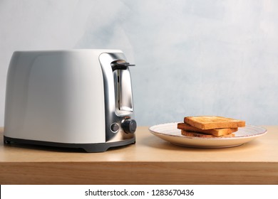 Toaster and plate with bread slices on table against light background - Shutterstock ID 1283670436
