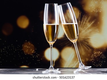 Toasting With Champagne Glasses Against Holiday Lights And New Year Fireworks