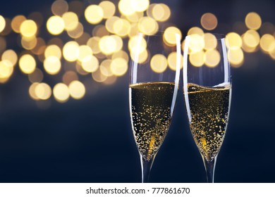 Toasting With Champagne Glasses Against Holiday Lights And New Year Fireworks