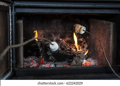 Toasting Marshmellows Using Sticks In An Indoor Wood-burner.