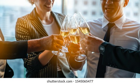 Toasting to success concept.Group of business people toast with champagne and smiling while standing close to each in bar.Friends clinking and toasting with glasses of champagne in lounge. - Powered by Shutterstock