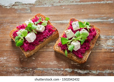 Toasts with hot beetroot hummus with horseradish and feta cheese and young sprouts of valerianella locusta