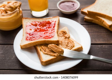 Toasts with peanut butter and jam on plate, over wooden background. American traditional breakfast concept