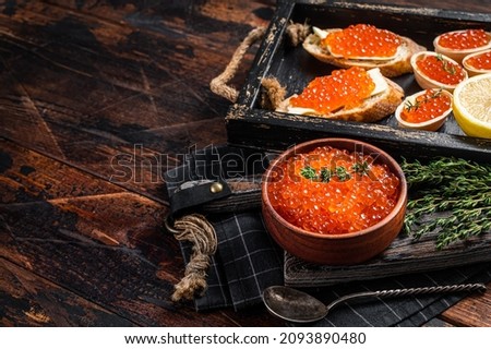 Toasts and Tartlets with Red caviar and butter in wooden tray. Wooden background. Top view. Copy space