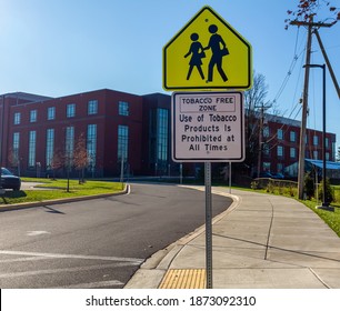 Tobacco Free Zone Sign With Student Crossing Sign In Front Of A Public High School In Maryland. No Tobacco Products Are Allowed In Premises To Avoid Second Hand Smoke Hazards