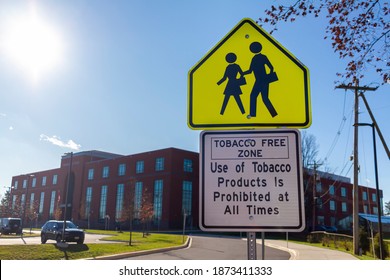 Tobacco Free Zone Sign With Student Crossing Sign In Front Of A Public High School In Maryland. No Tobacco Products Are Allowed In Premises To Avoid Second Hand Smoke Hazards