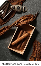 Tobacco leaves, cigars, and a cutter arranged on a dark surface create an elegant and rich ambiance for cigar enthusiasts