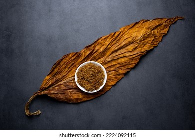 Tobacco leaves and cut tobacco on black background