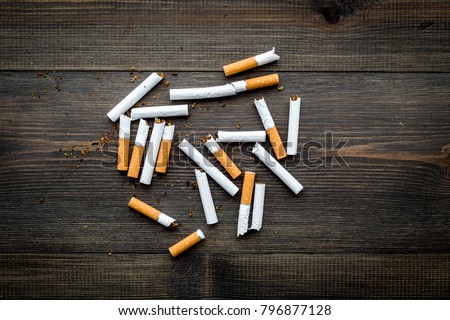 Tobacco. Scattered cigarettes on dark wooden background top view copy space