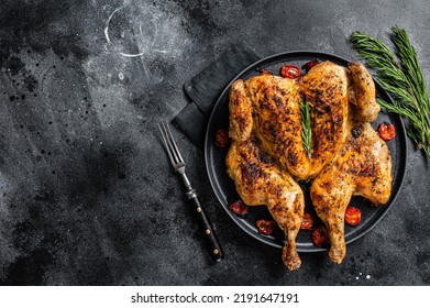 Tobacco whole chicken on plate with herbs and tomato. Black background. Top view. Copy space - Shutterstock ID 2191647191