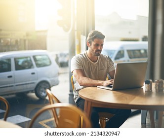 Todays tech allows you to work anywhere. Shot of a young man working on his laptop in a coffee shop.