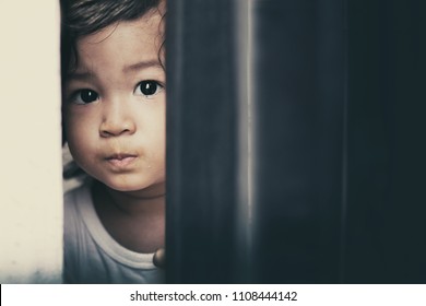 
Toddler Asian Baby Boy Sneak Peek Or Looking Through The Cap Of Metal Gate. Curiously Kid Look Sad,bored But Interesting Outside Things.He May Sick Or Imprison Or Safe Him From Outside Things.