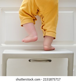 Toddler Baby Boy Climbed With His Feet On A High Chair To Climb On The Kitchen Cabinet. Child Safety Issues In The Home Room, Little Kid