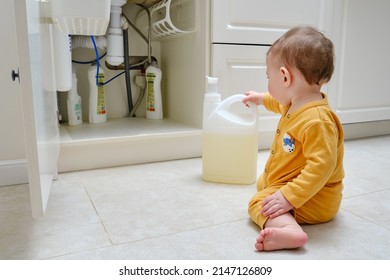 Toddler Baby Boy Is Playing With Detergents And Cleaning Products In An Open Kitchen Cabinet. Child Safety Issues In The Home Room, Little Kid