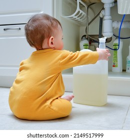 Toddler Baby Boy Is Playing With Detergents And Cleaning Products In An Open Kitchen Cabinet. Child Safety Issues In The Home Room, Little Kid