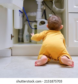 Toddler Baby Boy Is Playing With Detergents And Cleaning Products In An Open Kitchen Cabinet. Child Safety Issues In The Home Room, Little Kid