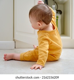 Toddler Baby Boy Is Playing With Detergents And Cleaning Products In An Open Kitchen Cabinet. Child Safety Issues In The Home Room, Little Kid