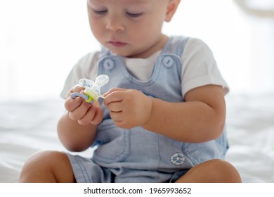 Toddler baby boy, playing with dummy, crying unhappy for the pacifier in children bedroom