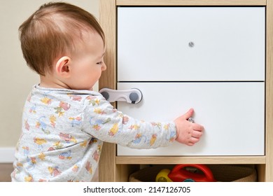 Toddler Baby Boy Rips Off A Cabinet Drawer With His Hand. The Child Holds The Cabinet Door Handle, Small Kid