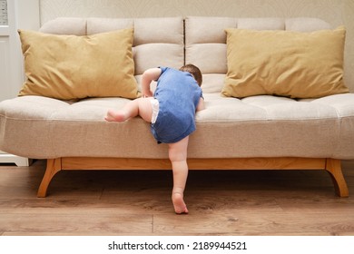 Toddler baby climbs on the sofa. Child boy learning to get off the bed. Kid age one year - Powered by Shutterstock