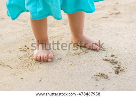 Toddler baby doing his first steps on the sand near the bank