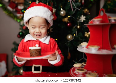 Toddler Baby Girl Eating Christmas Cake  In Front Of Christmas Tree