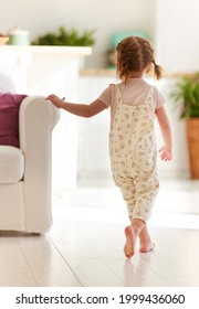 Toddler Baby Girl Running In Sunlit Living Room At Home