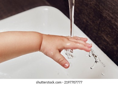 Toddler Baby Hand Is Washed Under Running Water From The Tap In The Sink. Child Learns To Wash His Hands