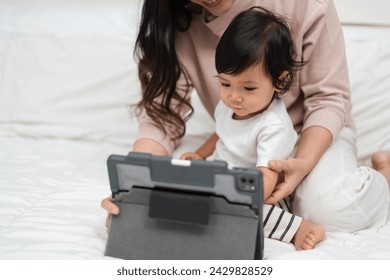 toddler baby with mother using digital tablet pc on a bed - Powered by Shutterstock