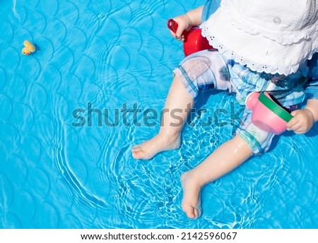 Toddler baby playing in the kiddie pool on a summer sunny day. Toddler summer activities