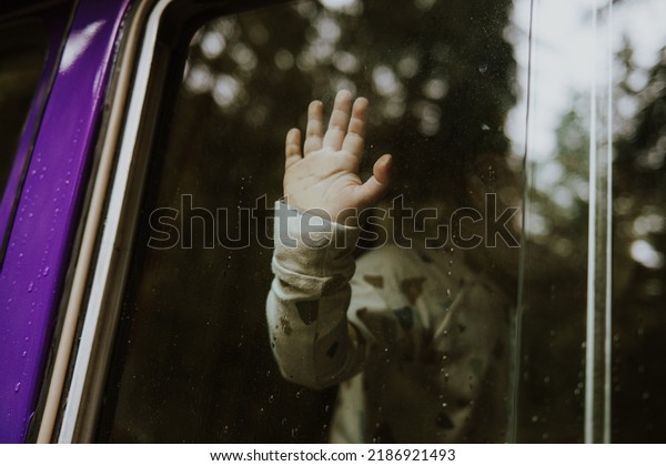 Toddler\
behind the car window and his hand on the\
window.