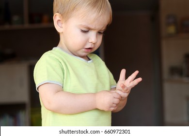 A Toddler Blond Boy Looking Musingly And Thoughtfully And Counting His Fingers, Close-up Emotional Portrait, Sign And Gesture Concept