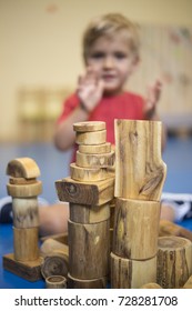 A toddler boy building with natural wood blocks in kindergarten. Montessori and Waldorf school concept. Autism therapy concept.