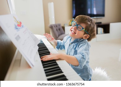 Toddler boy is having so much fun playing the piano. 