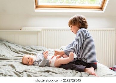 Toddler boy helping to change diaper to his sibling. Little mother's helper, caring older brother. - Shutterstock ID 2192729545