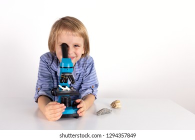 Toddler boy with a microscope a lesson of practical life on a white background