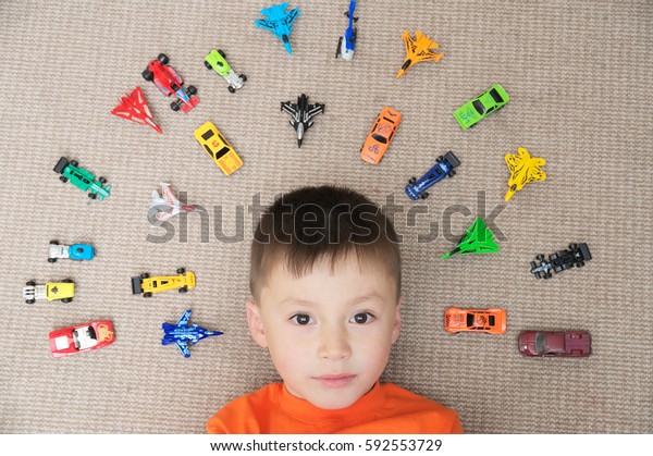 toddler boy playing\
with car collection on carpet. Transportation,airplane, plane and\
helicopter toys for children, miniature models.View from above.\
Many cars for little\
boys.