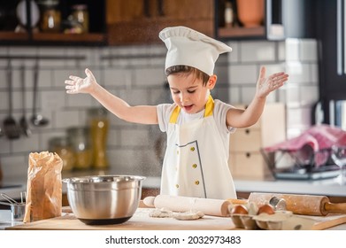 Toddler boy playing with the dough in the kitchen dressed as a chef. Child baking a cake