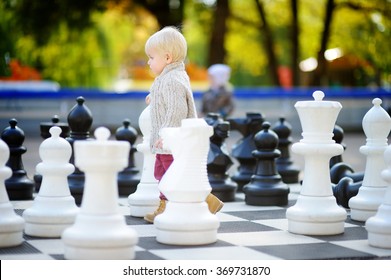Toddler boy playing giant chess outdoors
 - Powered by Shutterstock