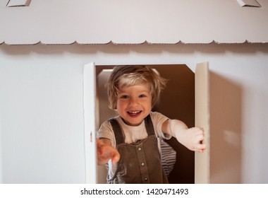 A Toddler Boy Playing Indoors With Cardboard House At Home.